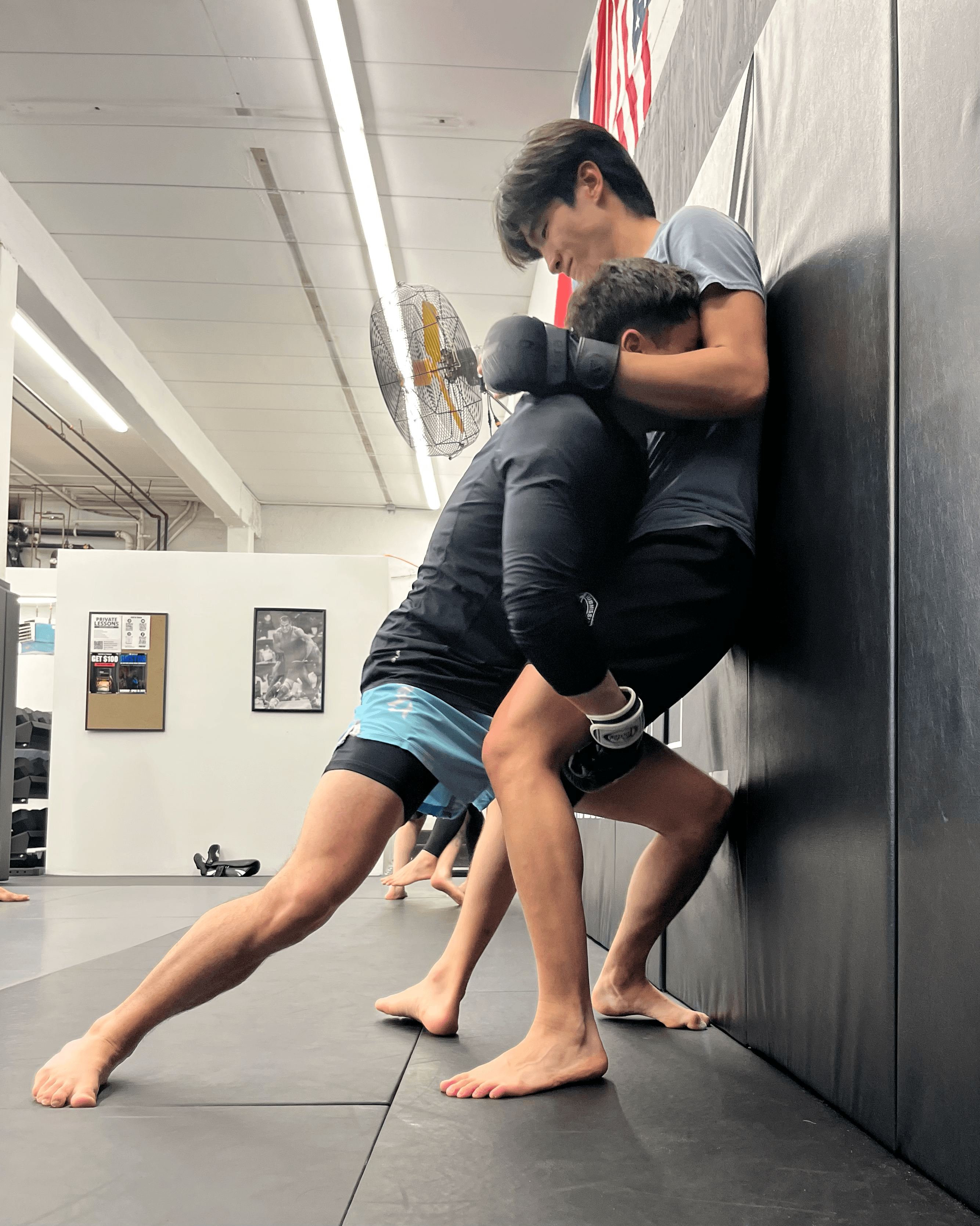 Students practicing MMA against a wall.