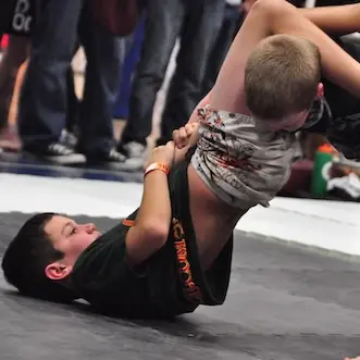 Photo of kid performing an armbar in a Jiu Jitsu competition.