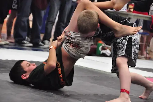 Photo of kid performing an armbar in a Jiu Jitsu competition.